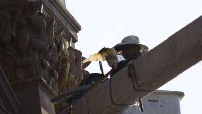 beekeeper lifted in bucket truck holding up backlit comb