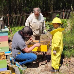 Dr. Zac Lamas works with a child and adult beekeeper